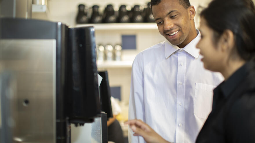 A woman showing a man how to use a coffee machine