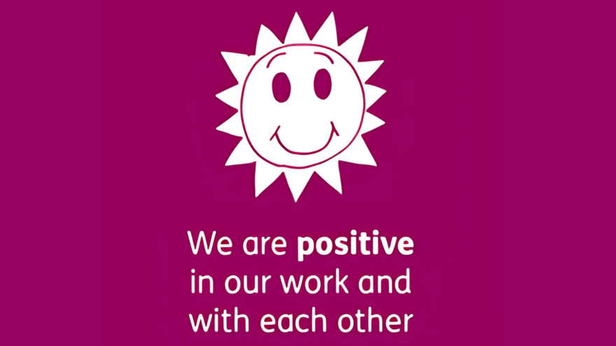 A picture of a sun with a smiley face. The caption underneath says: "We are positive in our work and with each other".