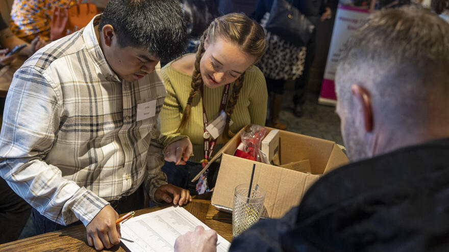 Supported internship learner, Arjhay helping attendees to sign in at the MTA employer awards.