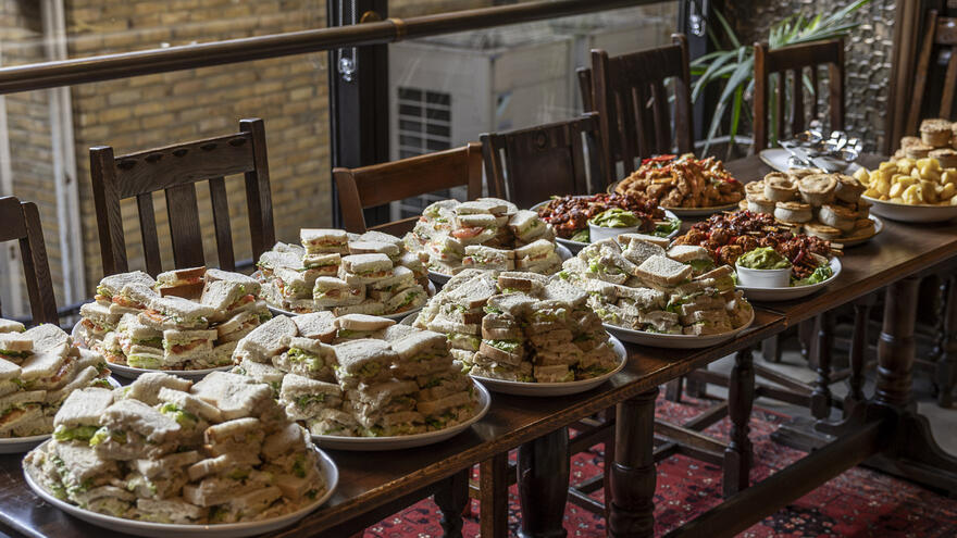 A picture of lots of sandwiches piled on a table.