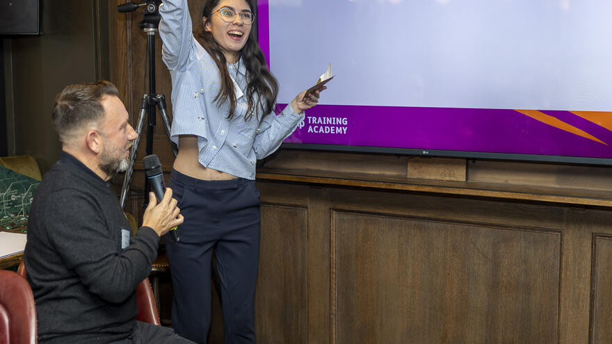 A man with a microphone and a woman cheering. 